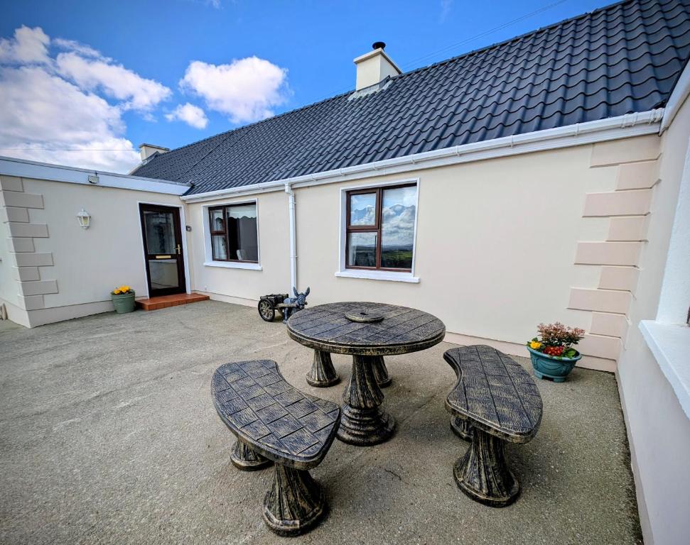 a patio with a table and four chairs in front of a house at The Brae Cottage in Burnfoot