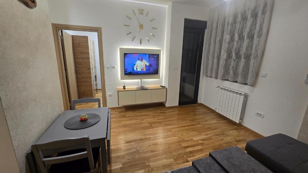 a living room with a table and a clock on the wall at Apartman Simić in Smederevo