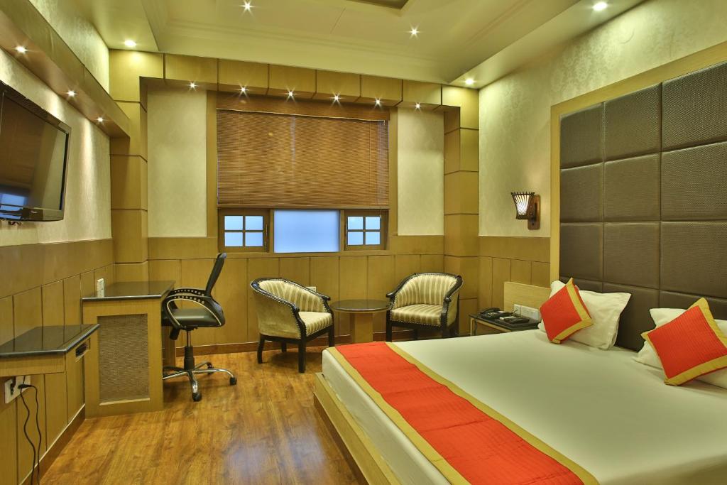 a hotel room with a bed and a desk and chairs at Hotel The Grand Chandiram in Kota