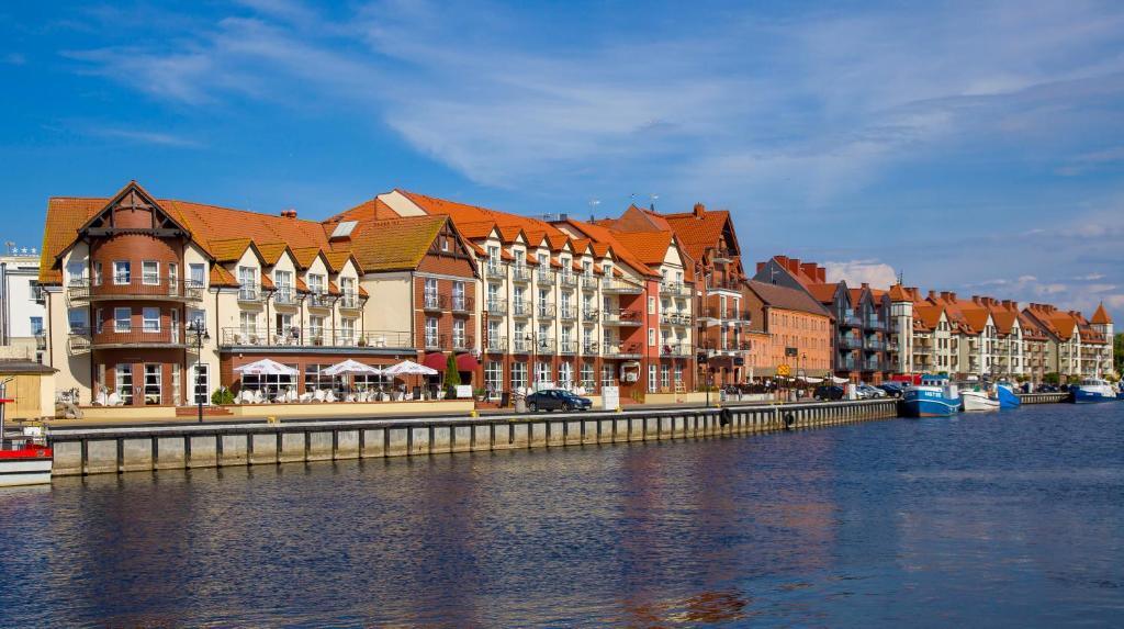 un groupe de bâtiments à côté d'une masse d'eau dans l'établissement Hotel Morze, à Ustka