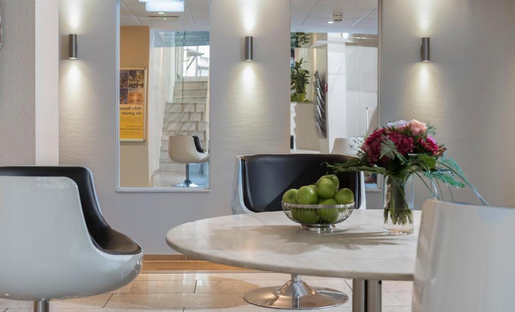 a table with a bowl of apples and flowers on it at Days Inn Dortmund West in Dortmund