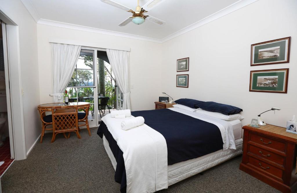 a bedroom with a bed and a desk and a window at Palm Beach Bed & Breakfast in Palm Beach