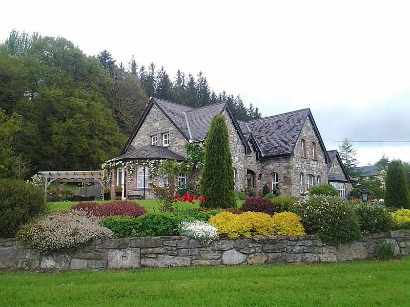 a house with a stone wall and flowers in a yard at Drumhierney Lodge in Leitrim