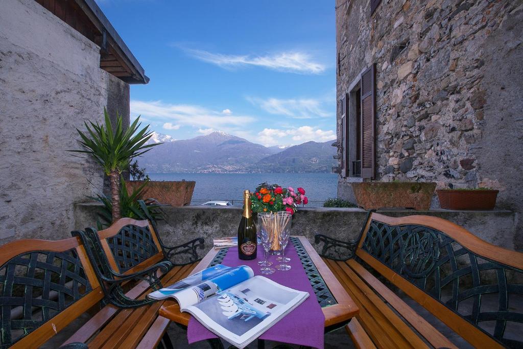 een tafel met een fles wijn en bloemen op een balkon bij Nobiallo Fantastico in Menaggio