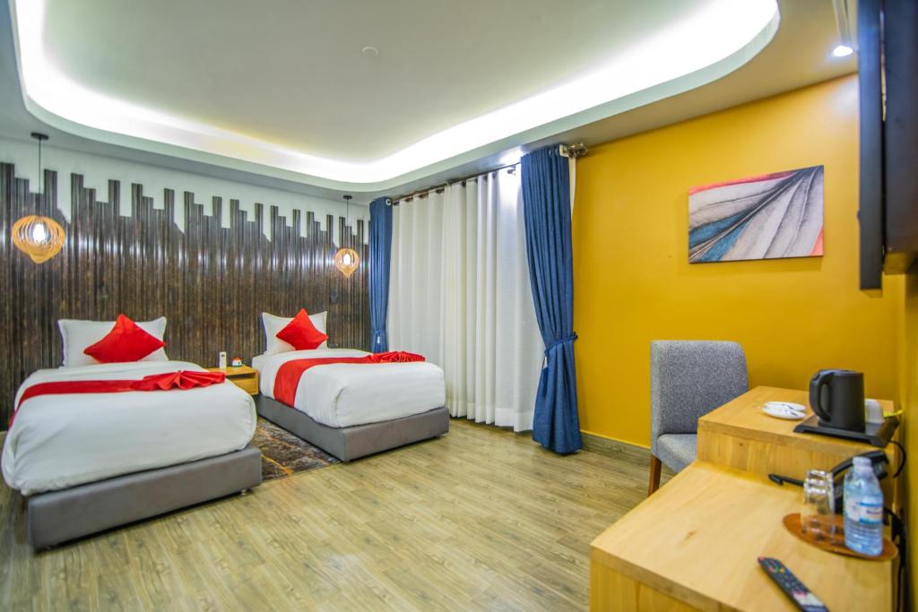 a hotel room with two beds and a desk at Hotel La vena in Kampala