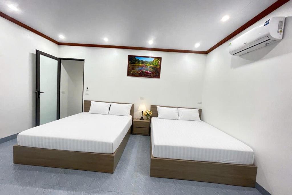 a bedroom with two beds and a tv on the wall at Đức Quỳnh Hotel in Ninh Binh