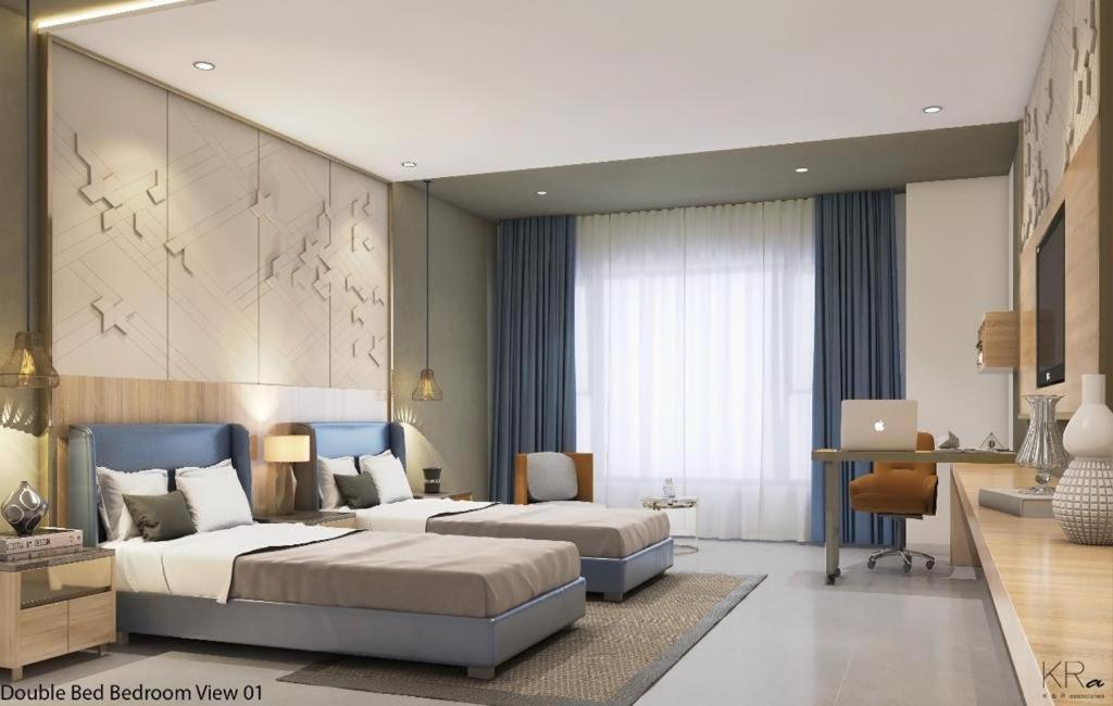 a bedroom with two beds and a desk with a laptop at Hotel Shubham Prestige RC Puram in Lingampalli
