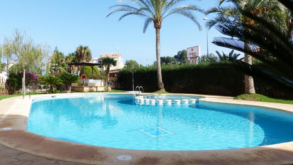 ein großer blauer Pool mit Palmen im Hof in der Unterkunft Playasol III El Conserje in Denia