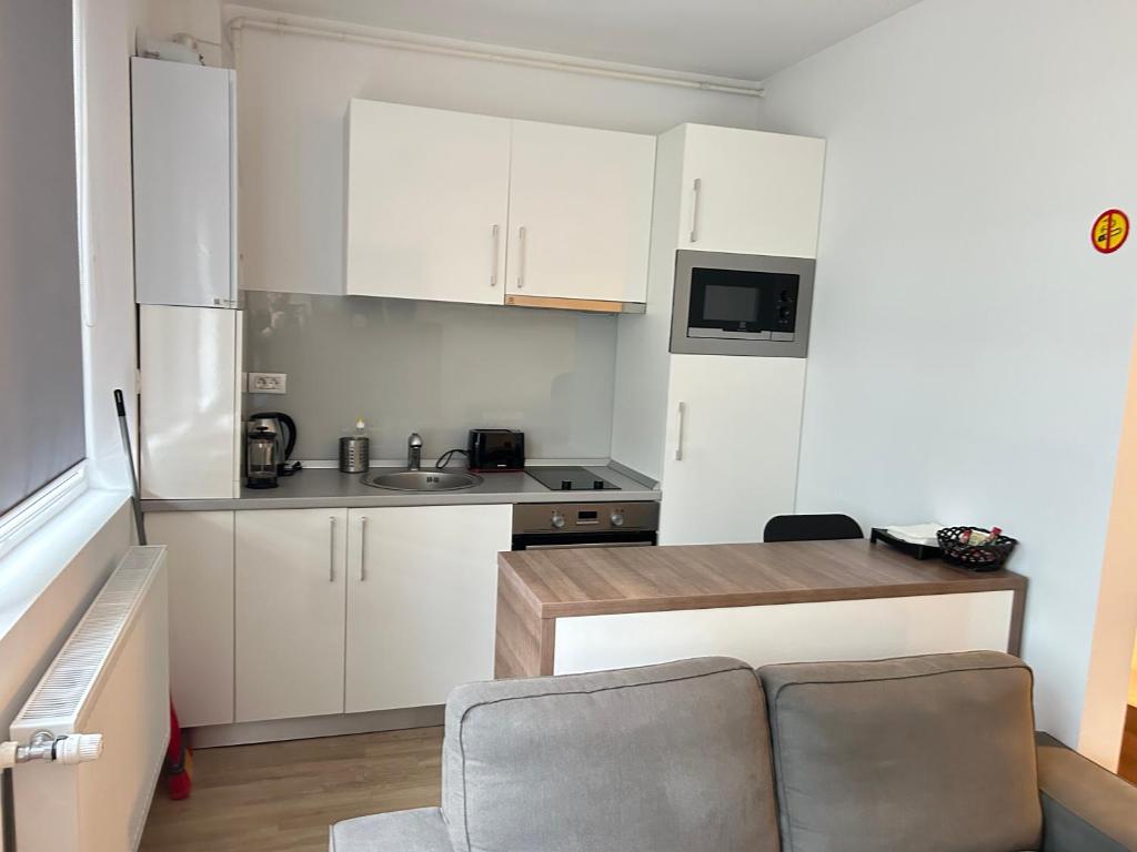 a small kitchen with white cabinets and a couch at Studio Pompeiu in Bucharest
