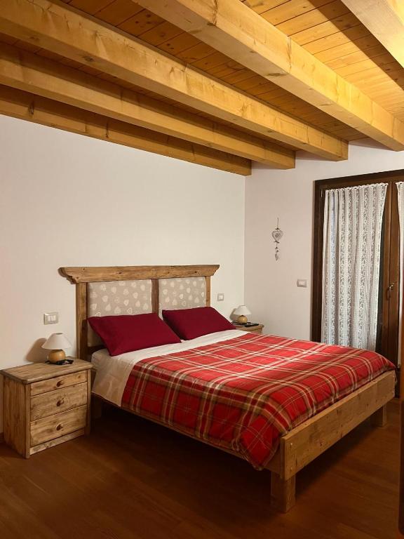 a bedroom with a wooden bed with red pillows at Casina sulle dolomiti in Borca di Cadore