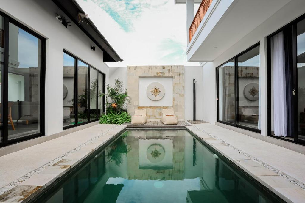 an indoor pool in a house with large windows at Dkenyeri Villa by Aayan in Tanah Lot