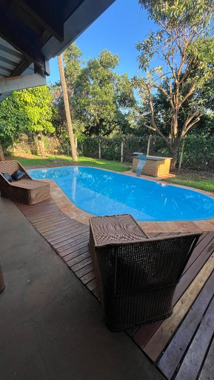 a swimming pool with two benches next to a wooden deck at A área Orioli in Jardinópolis