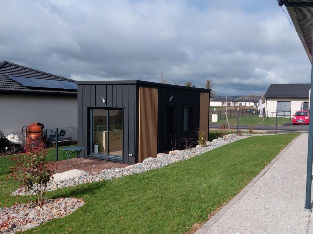 a small black house with a yard at Maison studio de jardin in Naucelles