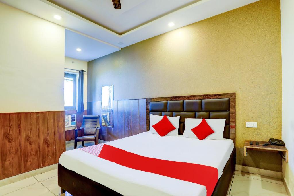a bedroom with a large bed with red pillows at Hotel O Elibrista in Meerut