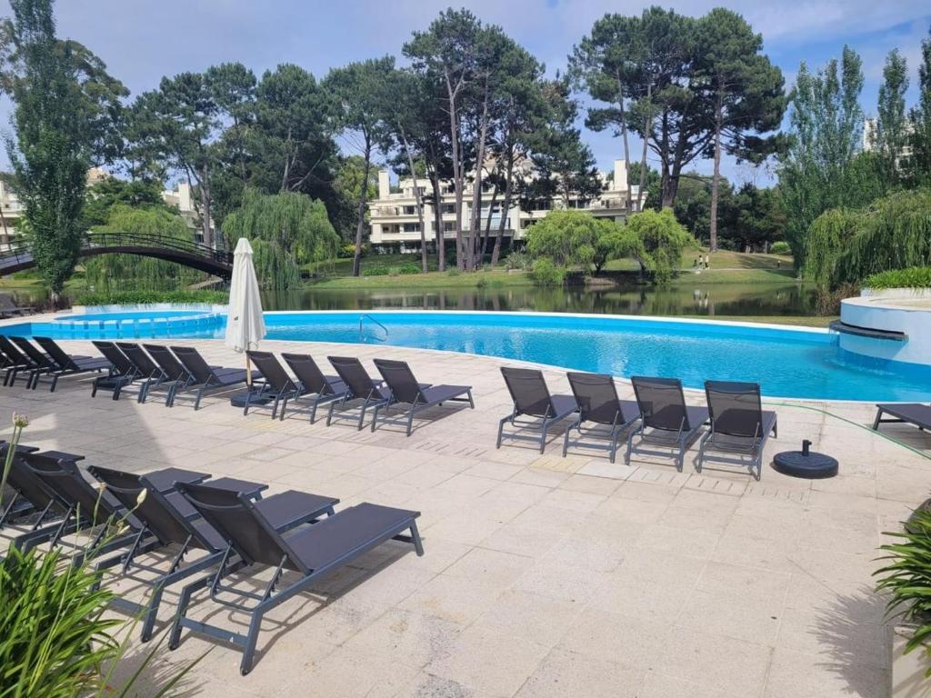 a group of lounge chairs next to a swimming pool at Green Park Solanas Monoambiente Punta del Este in Punta del Este