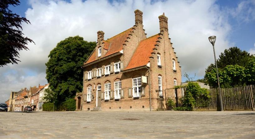 a large brick building with a red roof at B&B l'Heritage in Lo-Reninge