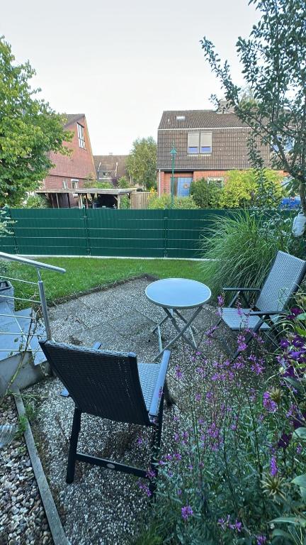 a patio with two chairs and a table in a yard at Quendel & Äpfel Ferienhaus in Neu Wulmstorf