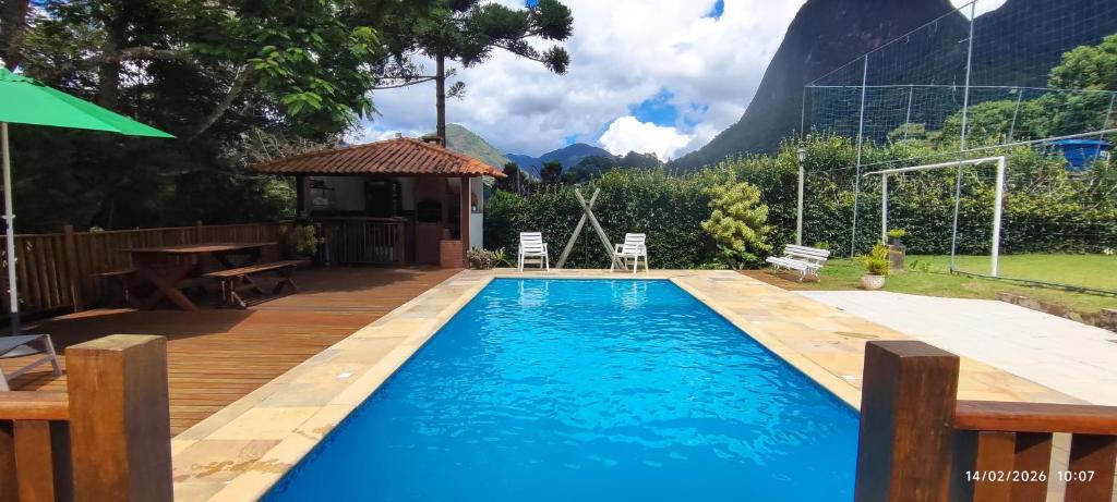 a swimming pool in a backyard with a wooden deck at Nossa casa in Petrópolis