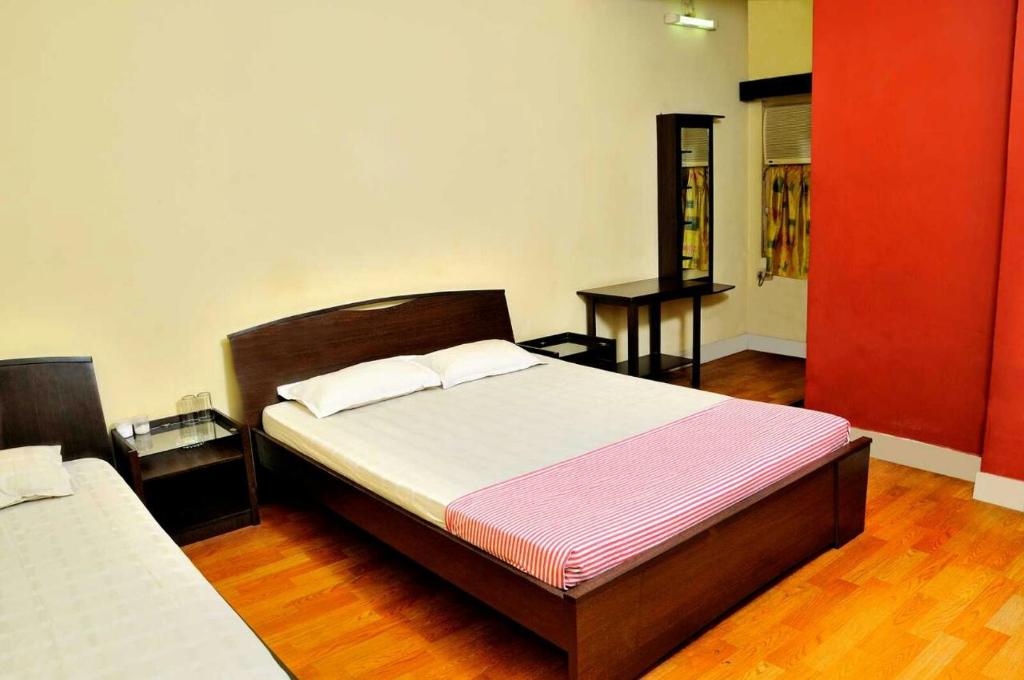 a bedroom with two beds and a red wall at Bothra Guest House in Kolkata