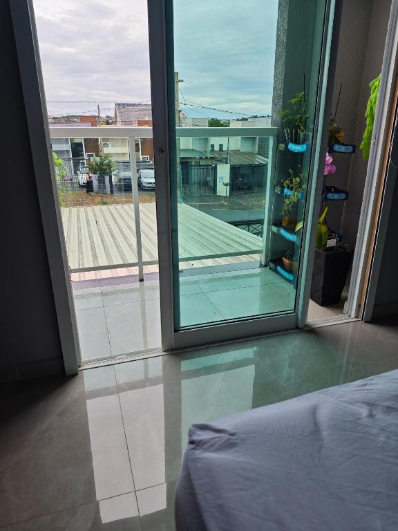 a bedroom with an open door to a balcony at suite ampla em sobrado com ar e garagem in Cascavel