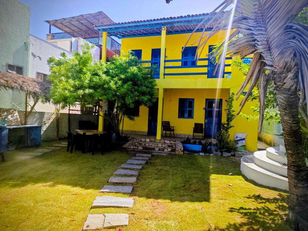 a yellow house with a table in the yard at Casa Jambo Canoa Quebrada in Canoa Quebrada