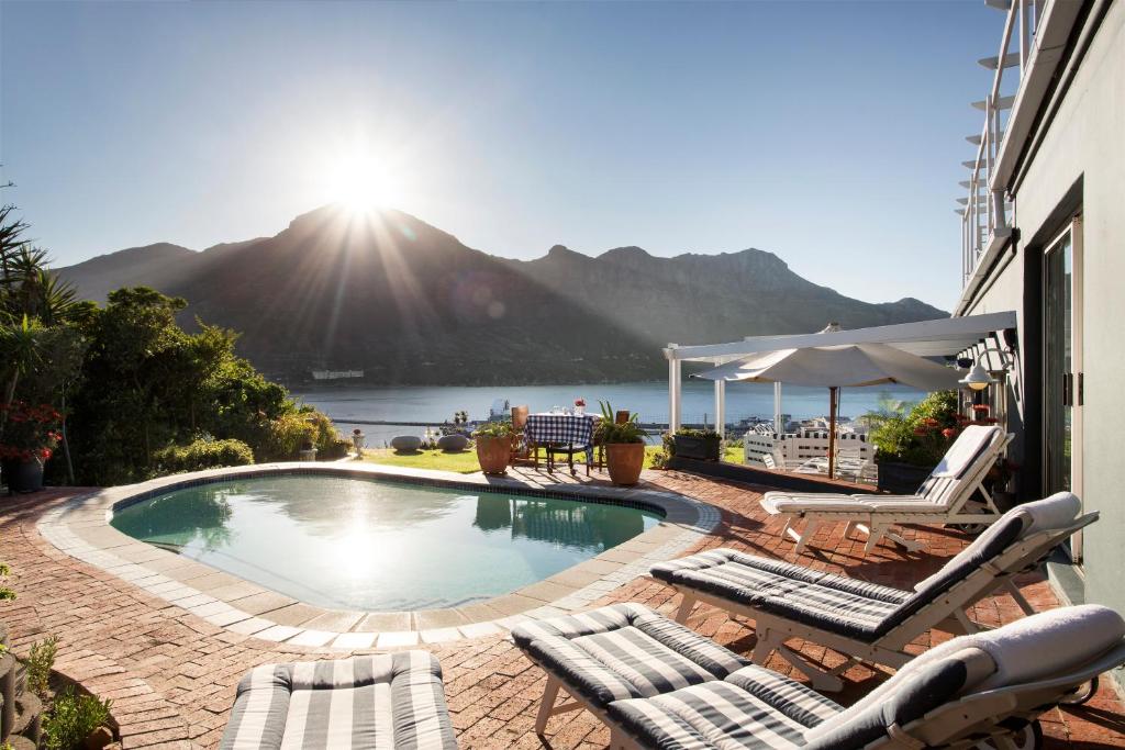 a swimming pool with chairs and a view of a mountain at Poseidon Guest House in Hout Bay