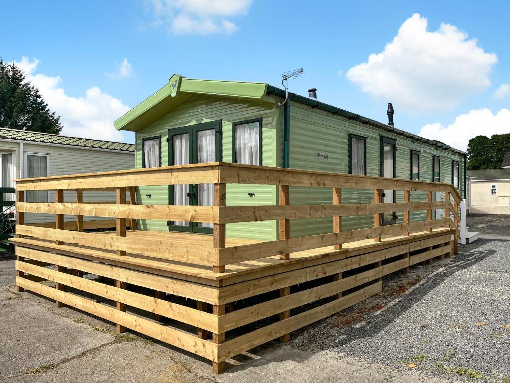 a green tiny house on a wooden deck at Peppy in Newton Stewart