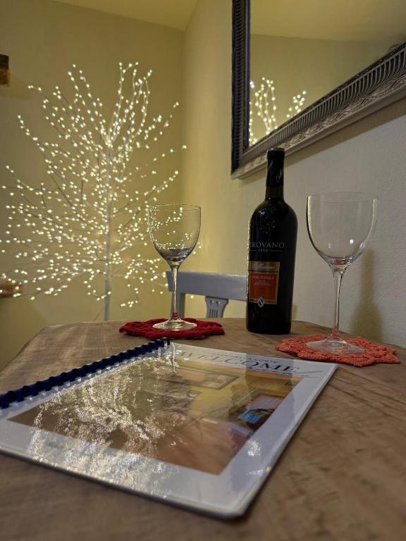 a table with two glasses and a bottle of wine at Casa nella Corte in Bellano