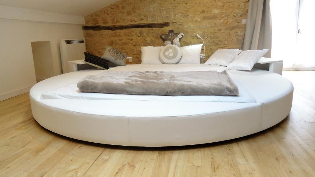 a large white bed in a room with a brick wall at Au Pied du CHÂTEAU - 5 à 11 personnes - Baignade-canoë-piste cyclable à 100 m in Castelnaud La Chapelle
