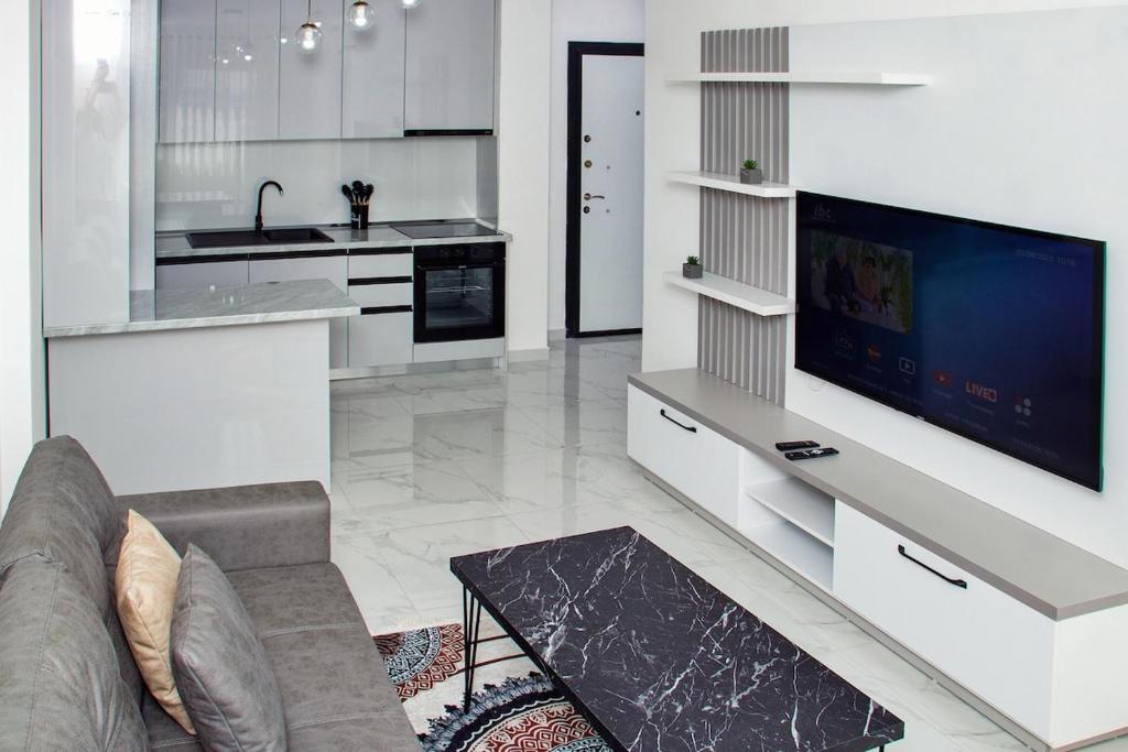 a living room with a couch and a tv in a kitchen at Flat in Shëngjin Beachfront Getaway in Shëngjin