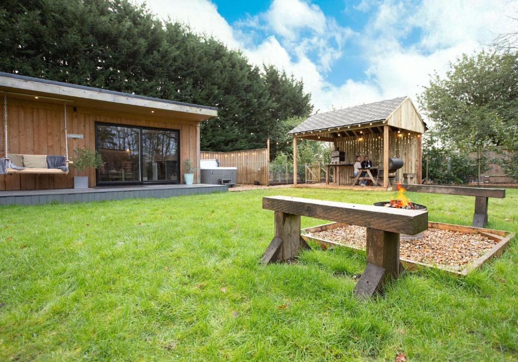 a wooden bench sitting in the grass in front of a house at City to Country Retreat Luxury Lodges with Hot Tub, BBQ, Fire Pit in Toppesfield