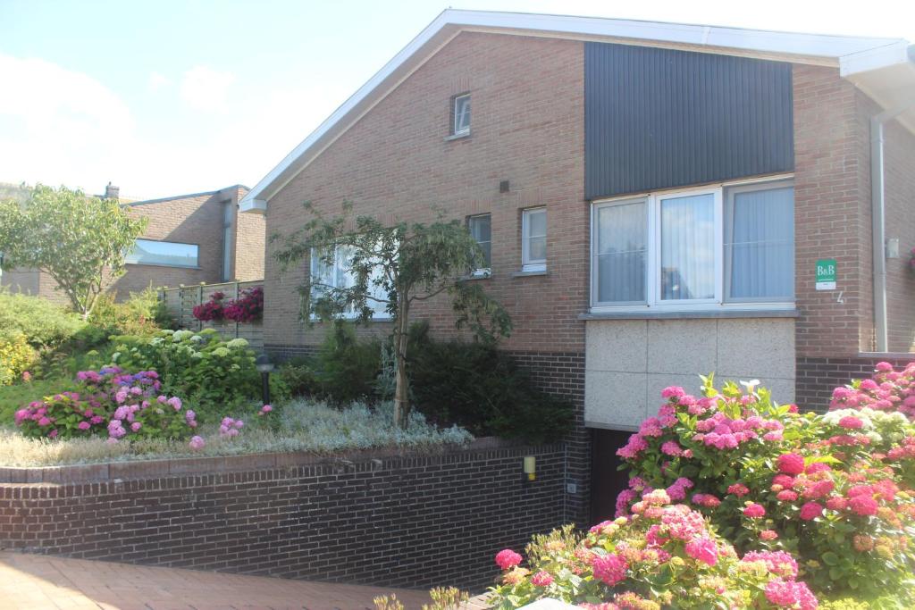 una casa de ladrillo con flores delante en B&B Vanloo en Middelkerke