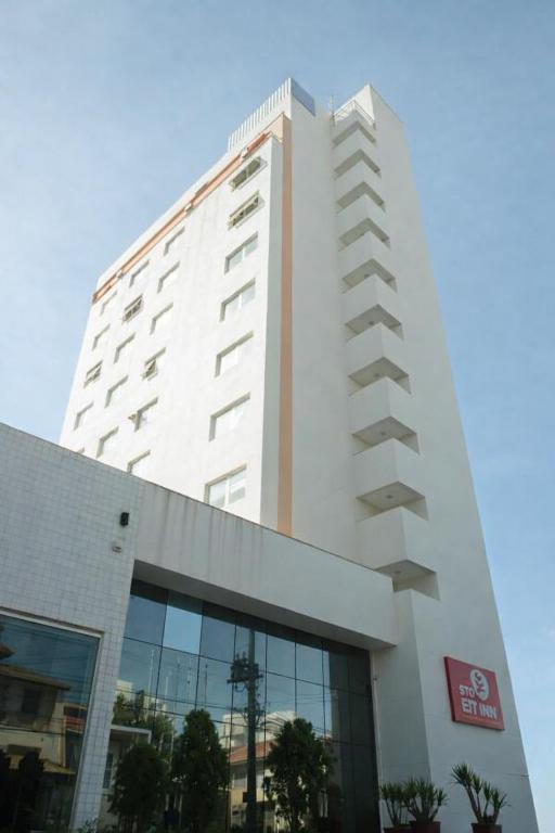 a tall white building with a sign on it at Stop Inn Cristiano Machado in Belo Horizonte