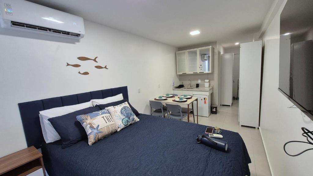 a bedroom with a blue bed and a kitchen at Studio Mare Alta in Tamandaré