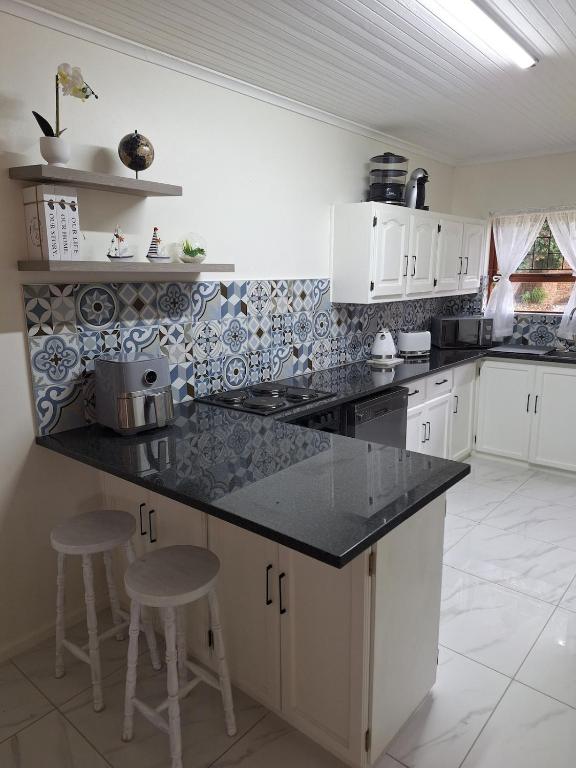 a kitchen with white cabinets and a black counter top at The Oyster Cove in Brenton-on-Sea
