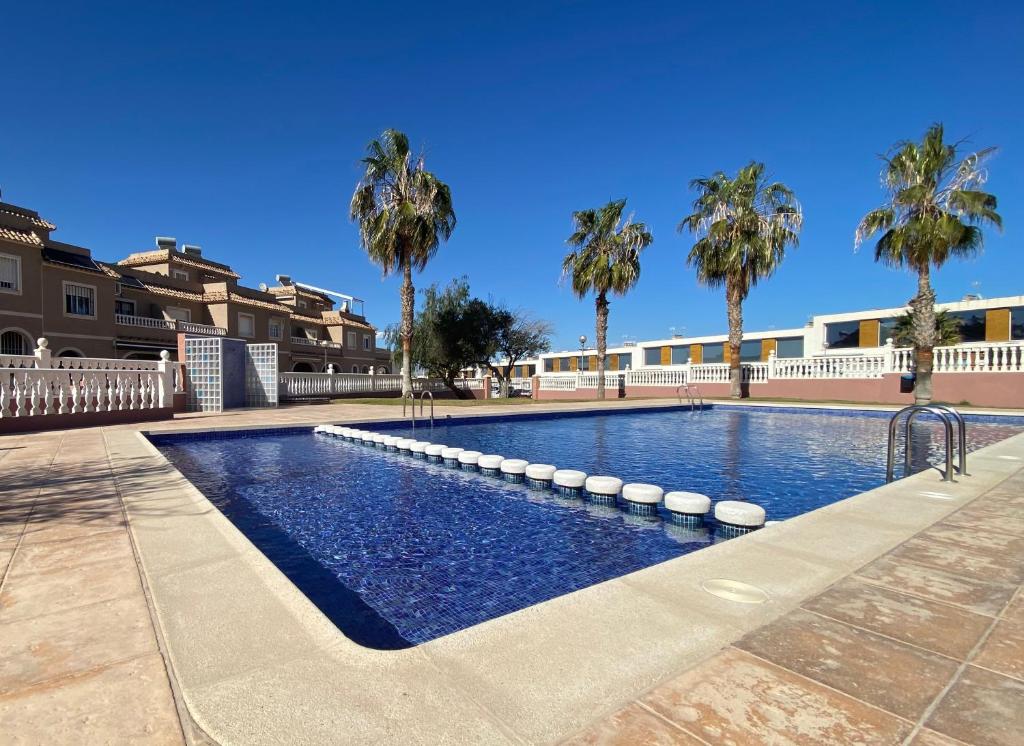 a swimming pool with palm trees in the background at CostaFlo in Gran Alacant