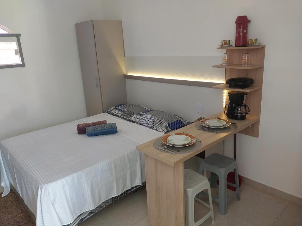 a bedroom with a bed and a table with plates on it at Microcasa loft in São Pedro da Aldeia