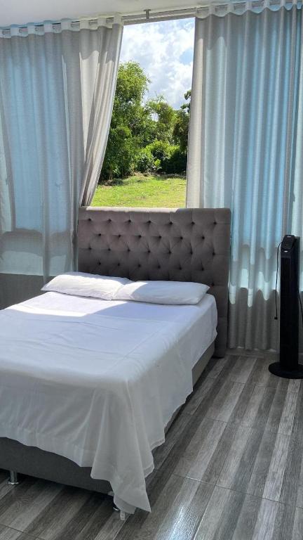 a bed in a bedroom with a large window at Casa o Habitación in Villeta