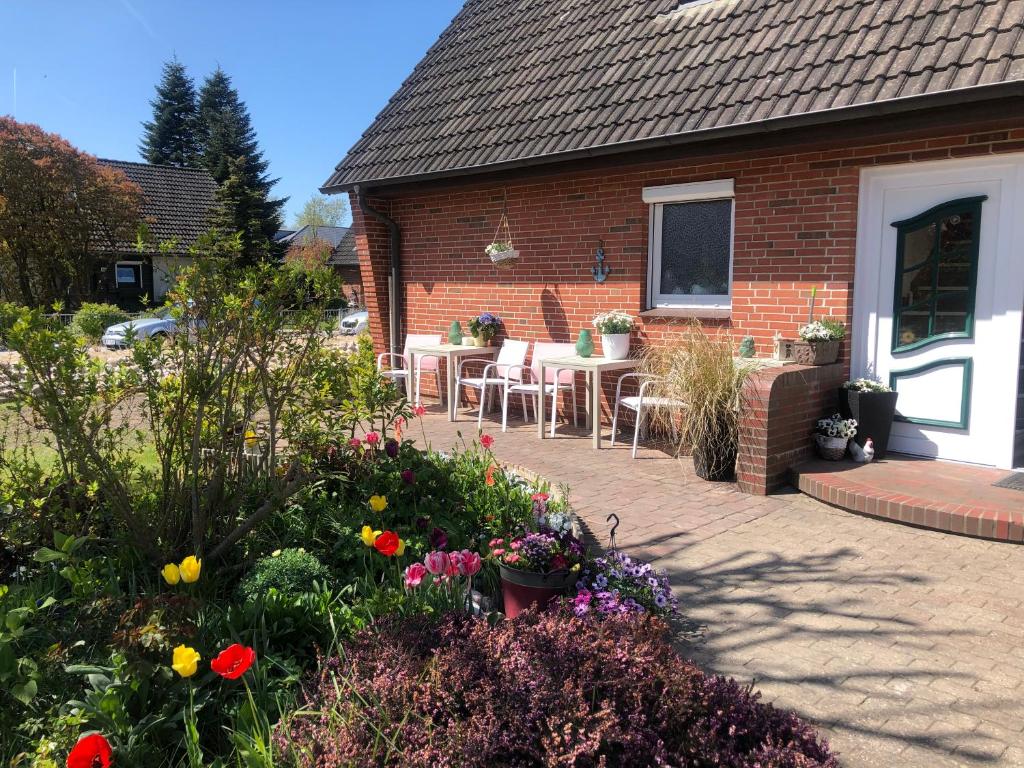 a patio with tables and chairs and flowers in front of a house at Gemütliches Inselnest mit großer Terrasse nahe Nordsee& Hafen in Tönning