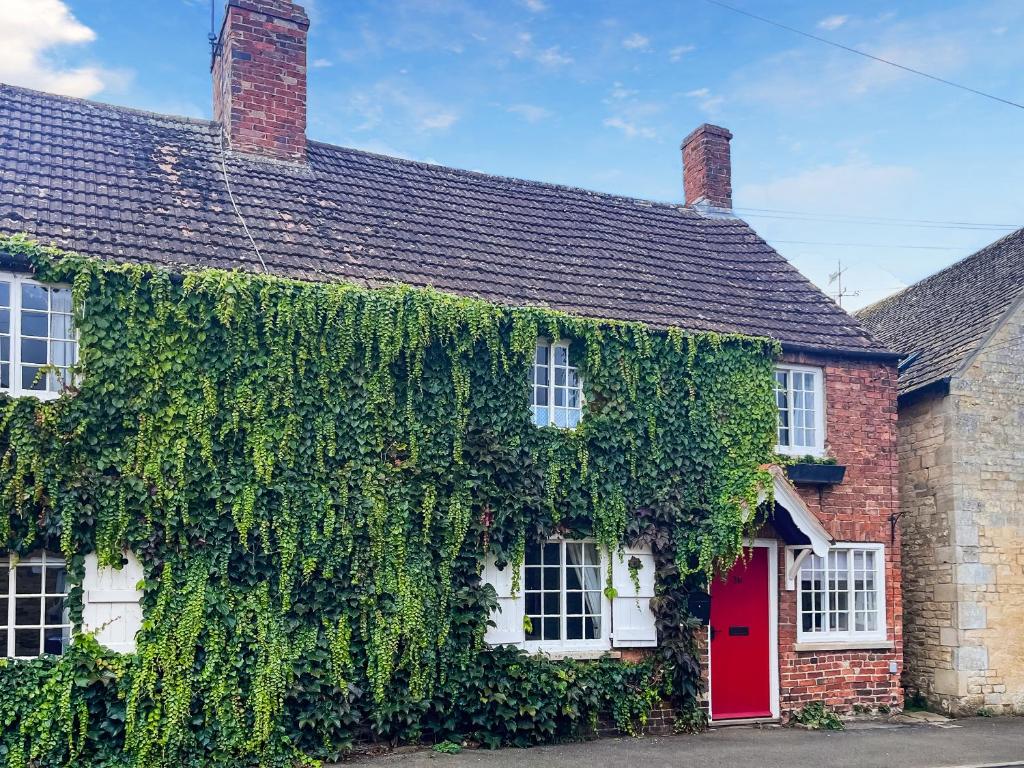 an ivy covered house with a red door at Teddy's Cottage in Market Overton