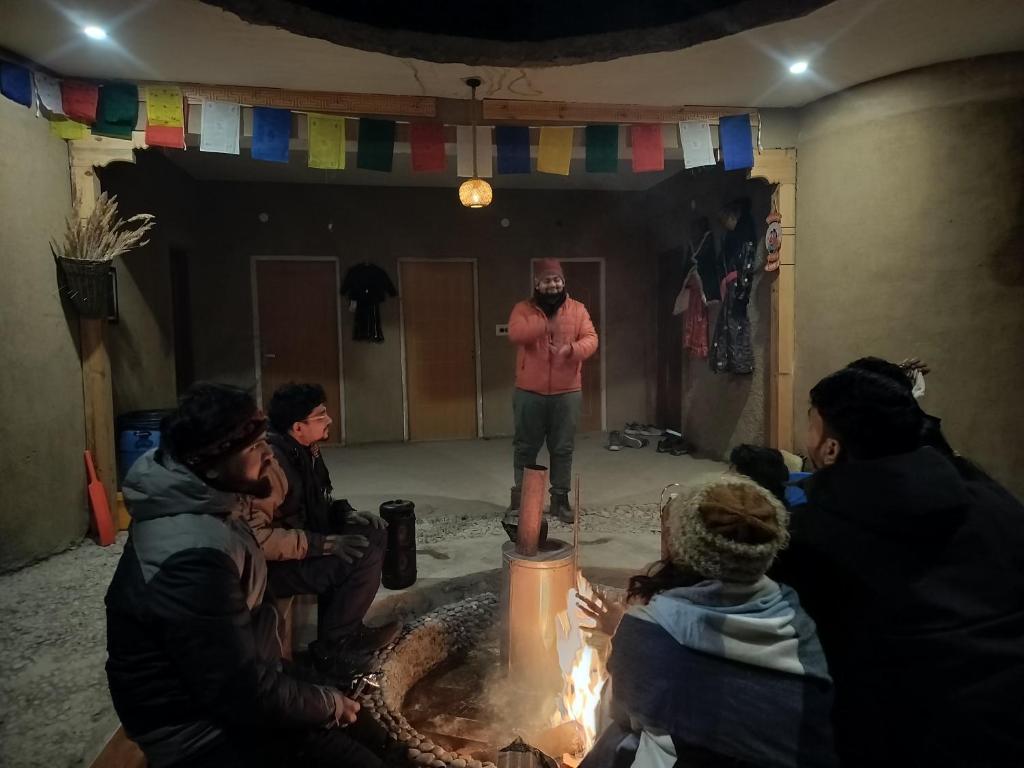 a man standing in front of a group of people around a fire at Aama Homestay in Tabo