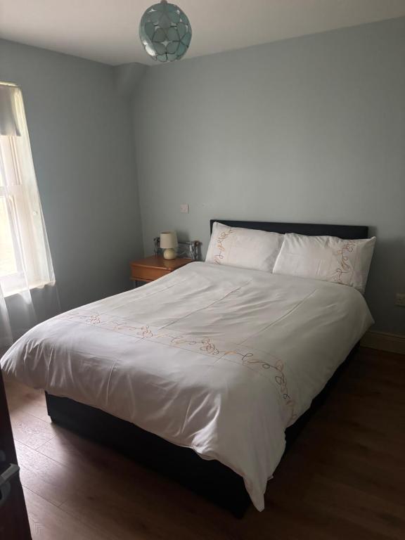 a bedroom with a white bed with a black headboard at Town Apartment in Ardara