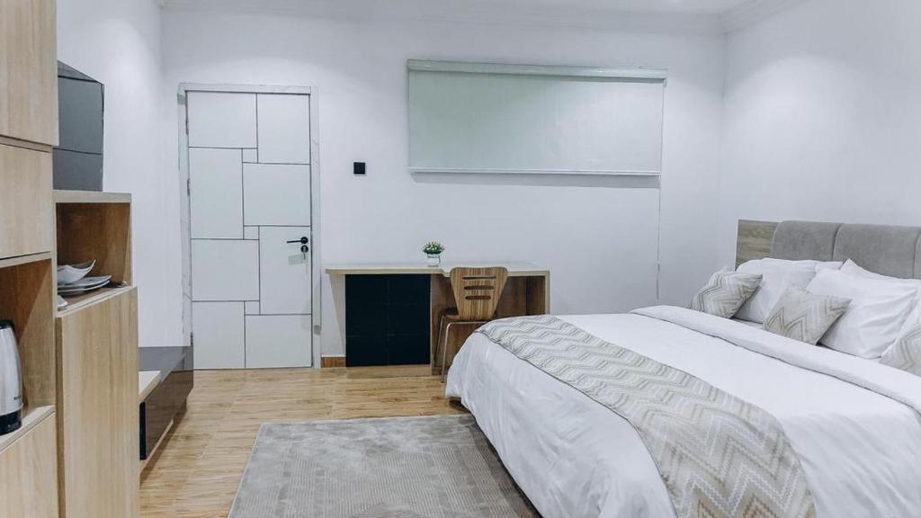 a white bedroom with a bed and a desk at French quarters apartments in Alaguntan