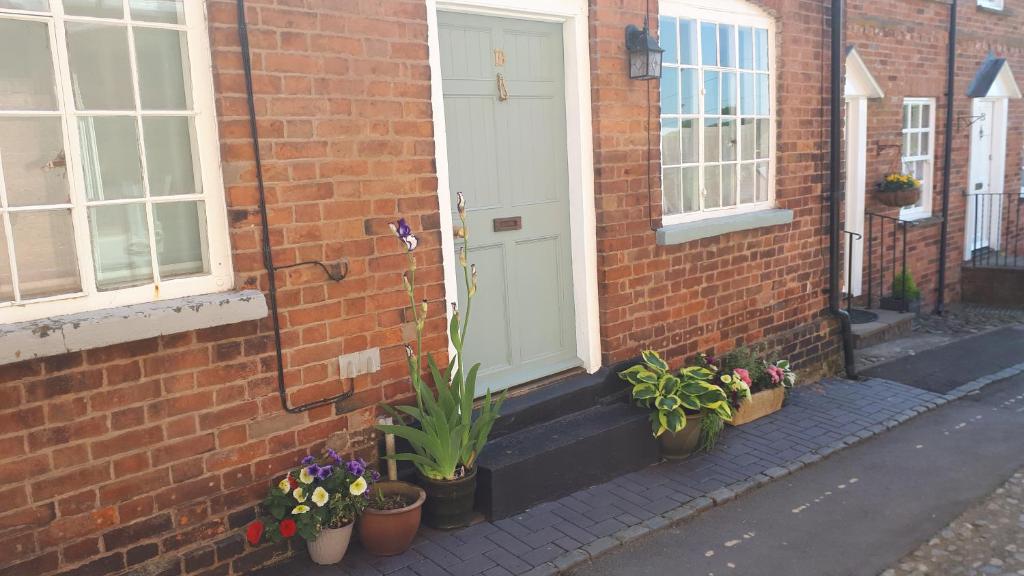 a brick building with potted plants and a white door at 19 Upper Linney in Ludlow
