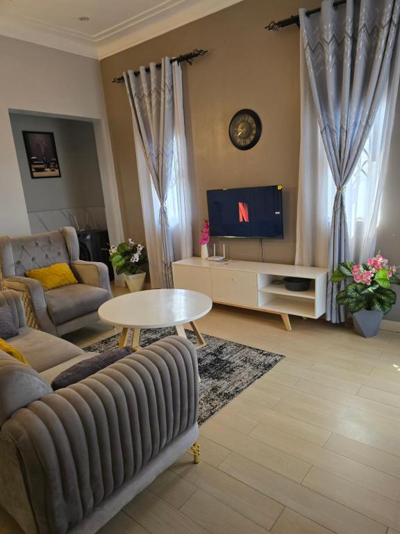 a living room with a couch and a tv at Dreamy Den Suites Kiwatule in Kampala