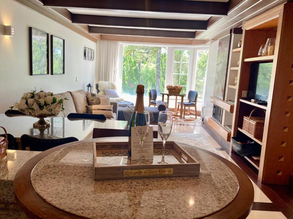 a living room with a table with a bottle of wine at Suíte Refúgio Mountain Village Laje de Pedra 3003 in Canela