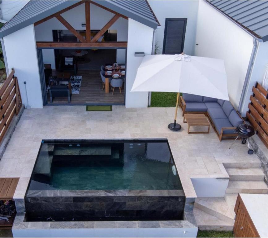 a pool in the middle of a patio with an umbrella at Luxury Oceanfront Villa Heated Infinity Pool in Petite Île