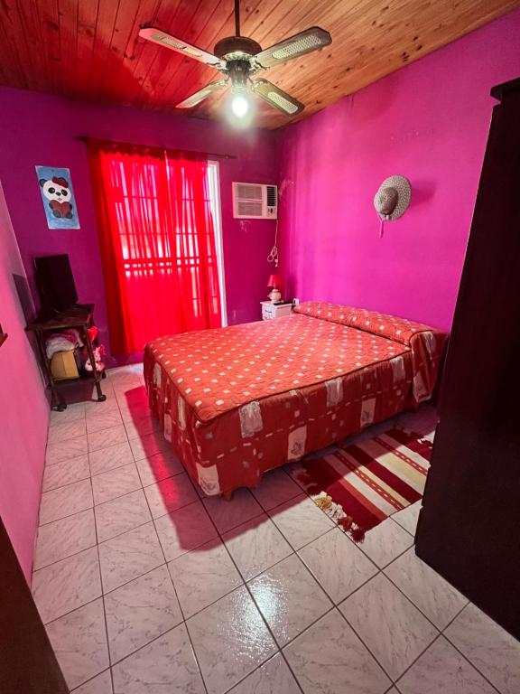 a pink bedroom with a bed and a ceiling fan at Rincón Bosc in Ramallo