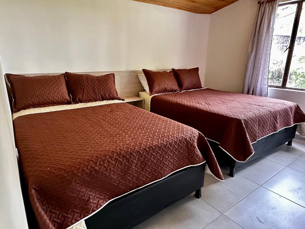 a bedroom with two beds and a window at Hotel Casa La Macana in Macanal