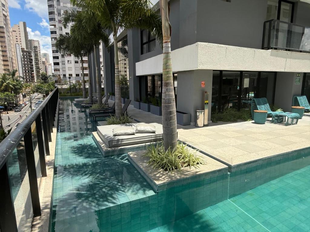 a swimming pool with a palm tree and a building at Luxo e Aconchego 1Qt Com Sacada GY03 proximo Vaca Brava in Goiânia
